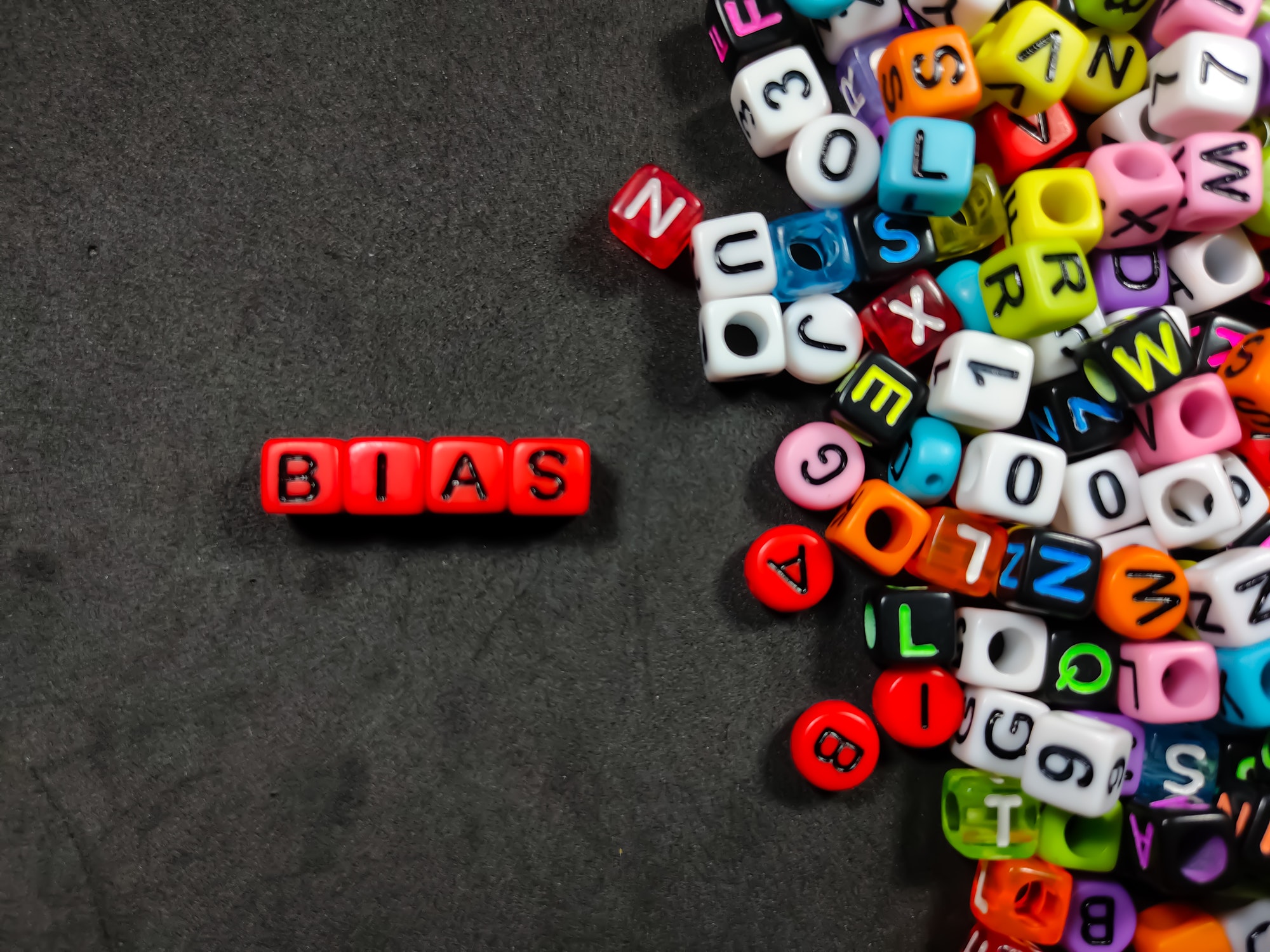 Selective focus.Colorful dice with color letter in word BIAS on black background.